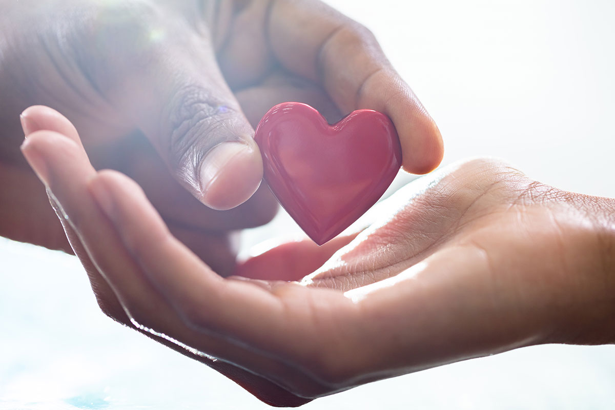 male hand giving red heart to female hand